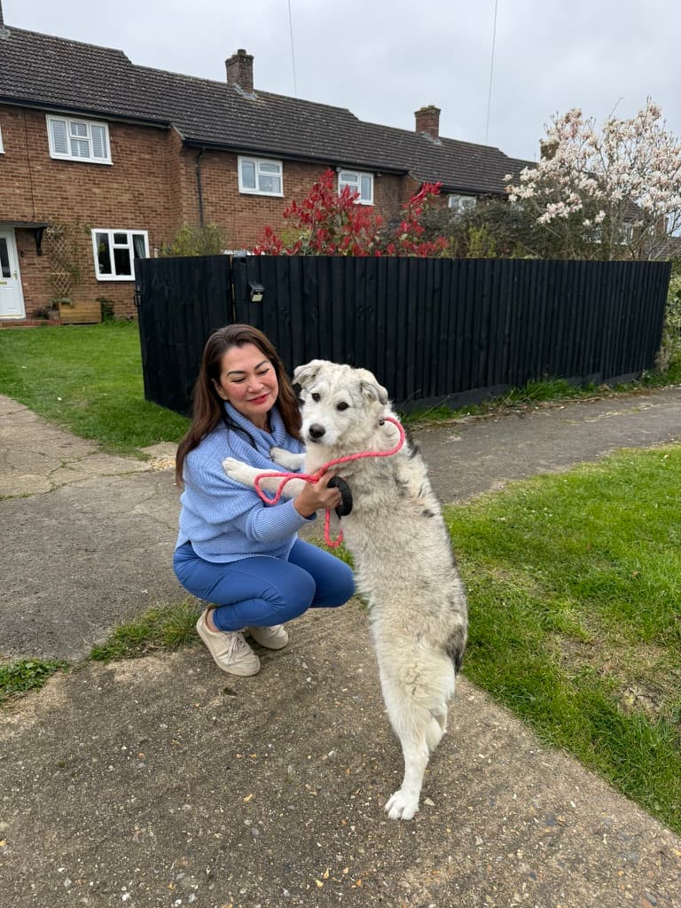 An adopter with her rescue dog on the driveway of their UK home, moments after arrival.